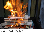 Огонь полыхает между дровами, сложенными друг на друга. Несколько сосновых и березовых поленьев сложены в квадратную башню, в центре которой ярко горят дрова и щепа. Стоковое фото, фотограф Andrew_Swarga / Фотобанк Лори