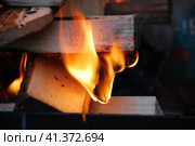 Огонь полыхает между дровами, сложенными друг на друга. Несколько сосновых и березовых поленьев сложены в квадратную башню, в центре которой ярко горят дрова и щепа. Стоковое фото, фотограф Andrew_Swarga / Фотобанк Лори