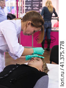 Cosmetologists perform a procedure to rejuvenate facial skin cosmetics Aravia at the festival of beauty Nevskie Berega in St. Petersburg 2012. Редакционное фото, фотограф Анна Кривицкая / Фотобанк Лори