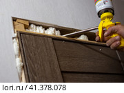 Installation of doors in the house. The master foams up the gaps between the door and the wall with polyurethane foam. Стоковое фото, фотограф Коханова Наталья / Фотобанк Лори