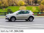 Side view rolling shot with Dacia Sandero Stepway subcompact car. Fast moving beige small hatchback with motion blur effect. Редакционное фото, фотограф Константин Григорьев / Фотобанк Лори
