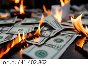 burning paper Money in fire falls on business table. The concept of bankruptcy, depreciation, devaluation, wastefulness and waste of money, AI. Стоковое AI-изображение, AI-художник Sergey Grishin / Фотобанк Лори