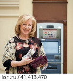 Mature blonde woman counting money near ATM. Стоковое фото, фотограф Андрей Аркуша / Фотобанк Лори
