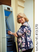 Mature blonde woman with credit card in hand near ATM. Стоковое фото, фотограф Андрей Аркуша / Фотобанк Лори