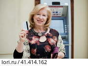 Mature blonde woman with credit card in hand near ATM. Стоковое фото, фотограф Андрей Аркуша / Фотобанк Лори
