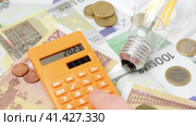 2023 Numbers on a Calculator. New Year Finance, Money Inflation and Budget Concept. High Cost of Heating and Electricity in the Next Year. Electric Cap, Light Bulb and Euro Banknotes on the Background. Стоковое видео, видеограф Марина Демидюк / Фотобанк Лори