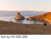 Baikal Lake in autumn. Olkhon Island. Tourists admire the sunset and take pictures of famous Shamanka Rock in sunset light on warm October evening. Autumn travel and outdoors recreation. Стоковое фото, фотограф Виктория Катьянова / Фотобанк Лори