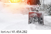 Snowblower removes snow, a man cleans the yard outside. Стоковое фото, фотограф Igor Skripachev / Фотобанк Лори
