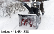 Snowblower removes snow, a man cleans the yard outside. Стоковое фото, фотограф Igor Skripachev / Фотобанк Лори
