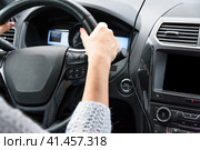 Young woman in blue sweater is sitting in the car behind the wheel. Female driver is driving the car in cloudy day. Woman hands on the steering wheel. Focus on the wheel. Молодая женщина в синем свитере сидит в машине за рулем. Женщина-водитель ведет машину в пасмурный день. Женские руки на рулевом колесе. Стоковое фото, фотограф Дмитрий Березнев / Фотобанк Лори