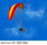 A colorful motorized paraglider flies against a blue sky. Sunny background with people paragliding. Illustration. Стоковая иллюстрация, иллюстратор Бузмакова Светлана / Фотобанк Лори