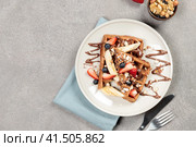 Chocolate Belgian waffles with fruits and nuts and chocolate sauce. Top view on a gray background. Стоковое фото, фотограф Bogdanova Mariia / Фотобанк Лори