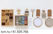 Concept of hand embroidery and crafts. Video of accessories for cross stitch and bead embroidery: hoops, scissors, set of needles, box with wooden beads, skeins of colorful threads mouline on bobbins in box. Стоковое видео, видеограф Виктория Катьянова / Фотобанк Лори