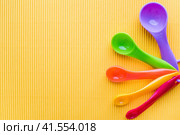 Мерные ложки на желтом фоне. Разноцветные пластиковые мерные ложки. Measuring spoons on a yellow background. Multi-colored plastic measuring spoons. Стоковое фото, фотограф Ольга Митряева / Фотобанк Лори