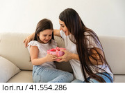Loving young mother congratulate excited small daughter with birthday give wrapped gift. Caring happy mom greeting make surprise with present for little girl child, celebrate together. Стоковое фото, фотограф Ирина Михайличенко / Фотобанк Лори