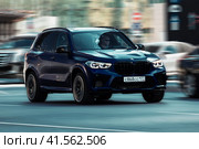 Car BMW X5m G05 in fast blurred motion in city traffic. Dark blue SUV speeding down a road. Редакционное фото, фотограф Константин Григорьев / Фотобанк Лори