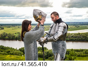 The lady puts on her knight a helmet. Knightly armor and weapon. Стоковое фото, фотограф Леонид Еремейчук / Фотобанк Лори