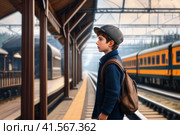 positive boy on railway station perron at fall noon. Travelling and vacations concept.. AI. Стоковое AI-изображение, AI-художник Sergey Grishin / Фотобанк Лори