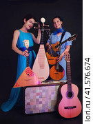 Women musicians in blue dresses with musical instruments on a black studio background. Happy artists with stringed musical instruments on a dark background. Стоковое фото, фотограф Андрей Журавлев / Фотобанк Лори