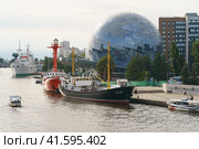 Kaliningrad, Russia - August 22, 2022:  Museum of the World Ocean. Building is in form of glass ball. Irbensky floating lighthouse. Moored on Pregolya River. SRT-129 is medium fishing trawler. Редакционное фото, фотограф YuryKara / Фотобанк Лори