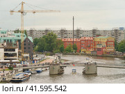 Kaliningrad, Russia - June 20, 2022: Cityscape in day. Bank of Pregol River and the Fishing village. Famous touristic location. New buildings. Yubileyny bridge. Construction crane. New buildings. Редакционное фото, фотограф YuryKara / Фотобанк Лори