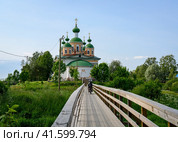 Wooden bridge leading to the Cathedral of Our Lady of Smolensk on an island among the woods in Olonets, Karelia, in summer (2023 год). Стоковое фото, фотограф Сергей Фролов / Фотобанк Лори