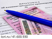 Водительское удостоверение, свидетельство о регистрации тс и авторучка лежат на бланке протокола об административном правонарушении (2023 год). Редакционное фото, фотограф Анна Аникова / Фотобанк Лори