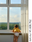 The child is alone by the window, lost in thought and risking their safety. Kid aged two years. Стоковое фото, фотограф Андрей Журавлев / Фотобанк Лори