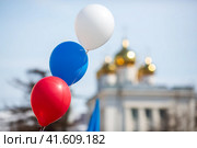 Цветные воздушные шары на фоне собора. Воздушные шары цветов российского флага: белого, синего и красного. Малая глубина резкости. Магадан, Магаданская область, Россия. Стоковое фото, фотограф Андрей Степанов / Фотобанк Лори
