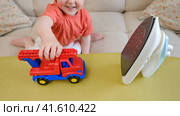 The baby must refrain from playing with a hot iron in the living room due to the potential danger it poses. Children need to be carefully monitored to avoid any incidents. Kid aged about two years. Стоковое фото, фотограф Андрей Журавлев / Фотобанк Лори