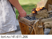 A blacksmith in a forge forges metal. Blacksmithing in retro style outdoors. Стоковое фото, фотограф Андрей Журавлев / Фотобанк Лори