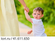 Baby looks back at his family home, feeling the weight of the separation. The mother and child hold hands tightly, trying to overcome the stress and depression together. Kid aged about two years. Стоковое фото, фотограф Андрей Журавлев / Фотобанк Лори
