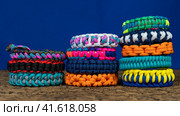 Lots of braided paracord bracelets on a blue background. Стоковое фото, фотограф Артем Лукин / Фотобанк Лори