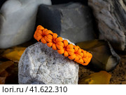 Braided paracord bracelet on the background of stones. Handmade, creative design. Стоковое фото, фотограф Артем Лукин / Фотобанк Лори