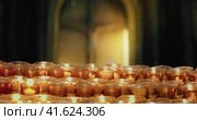Burning candles in the church. Orthodox cross with crucifixion of Jesus Christ. Christian faith in G. Стоковое видео, видеограф Igor Tichonow / Фотобанк Лори