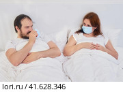 A man is protected by a medical mask from infection lying in a white bed, concept. Quarantine isolation problems due to the coronavirus epidemic. Стоковое фото, фотограф Андрей Журавлев / Фотобанк Лори