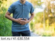 Abdominal pain when walking outdoors, man with stomach ache on nature background. Стоковое фото, фотограф Станислав Тарко / Фотобанк Лори
