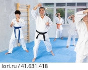 Group of teenagers in kimonos following karate sensei through kata exercises. Стоковое фото, фотограф Яков Филимонов / Фотобанк Лори