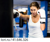 Asian woman in boxing gloves practicing punches on punchbag in gym. Стоковое фото, фотограф Яков Филимонов / Фотобанк Лори