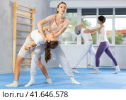 Young woman applying inverted headlock during mock bout in self-defense training. Стоковое фото, фотограф Яков Филимонов / Фотобанк Лори