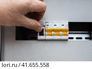 A man hand switches the toggle switches in the electrical panel, close-up. Electricity supply. (2023 год). Редакционное фото, фотограф Коханова Наталья / Фотобанк Лори