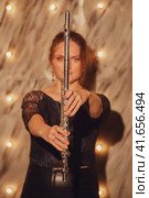 The flutist, a female musician, played her instrument under the illuminated concert lights at the musical entertainment. Стоковое фото, фотограф Андрей Журавлев / Фотобанк Лори