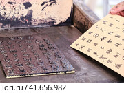 A man takes a printed sheet of paper. Cyrillic alphabet for printing in vintage style. Printing books old retro method. Стоковое фото, фотограф Андрей Журавлев / Фотобанк Лори