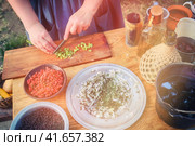 Life of the first pioneers of America. The girl prepares food in the kitchen for the first settlers Alaska, Klondike of America, historical reconstruction. Female hand cut salad on wooden Board in US. Стоковое фото, фотограф Андрей Журавлев / Фотобанк Лори