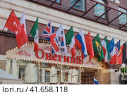 Moscow \ Russia 06 10 2019: Flags of different countries of the world over the Onegin restaurant on Arbat street. Restaurant "Onegin" in the domain of the Central street of Moscow. Редакционное фото, фотограф Андрей Журавлев / Фотобанк Лори