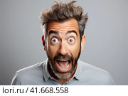 A young handsome man with a beard in a casual sweater on a gray background is afraid and shocked by surprise. Generated by AI. Стоковое AI-изображение, AI-художник Ярославский Максим / Фотобанк Лори