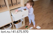 Toddler baby opened the cabinet drawer with pills and medicine. Child boy holding a pack of pills in the home living room. Kid aged about two years (age one year nine months) Стоковое видео, видеограф Андрей Журавлев / Фотобанк Лори