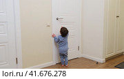 Little baby opens the door. Child pulls the door handle with the lock closed. Kid about two years old (age one year nine months) Стоковое видео, видеограф Андрей Журавлев / Фотобанк Лори