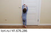 Little baby opens the door. Child pulls the door handle with the lock closed. Kid about two years old (age one year nine months) Стоковое видео, видеограф Андрей Журавлев / Фотобанк Лори