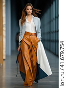 Stylish young girl with brown hair on the catwalk. She is wearing a brown leather Full-length photo. Generated by AI. Стоковое AI-изображение, AI-художник Ярославский Максим / Фотобанк Лори